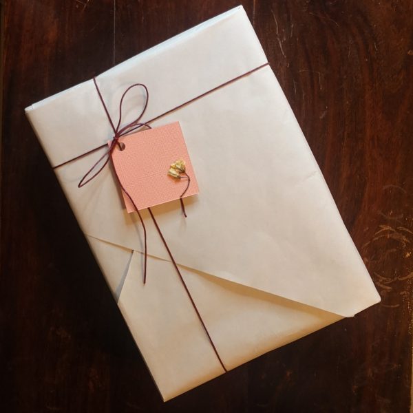 Gift wrapped with beige wrapping paper, hemp twine and a coral colour handmade pressed flower gift tag