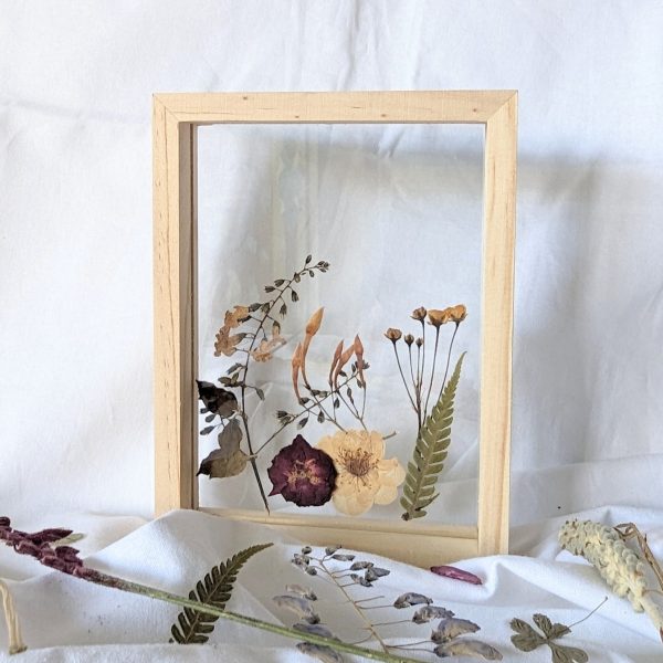 A sample of framed artwork using Florapeutic's Pressed Flower Art DIY Kit standing alone on a flat surface